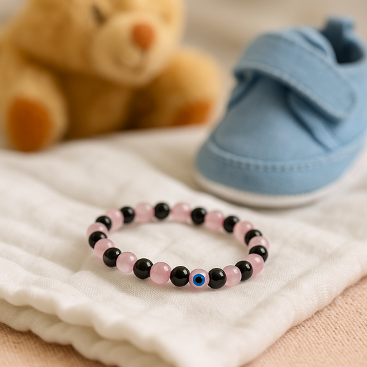 Rose Quartz Obsidian mix Children’s Nazar Suraksha, Evil Eye Protection Bracelet on a soft surface with a teddy bear and baby shoe in the background.