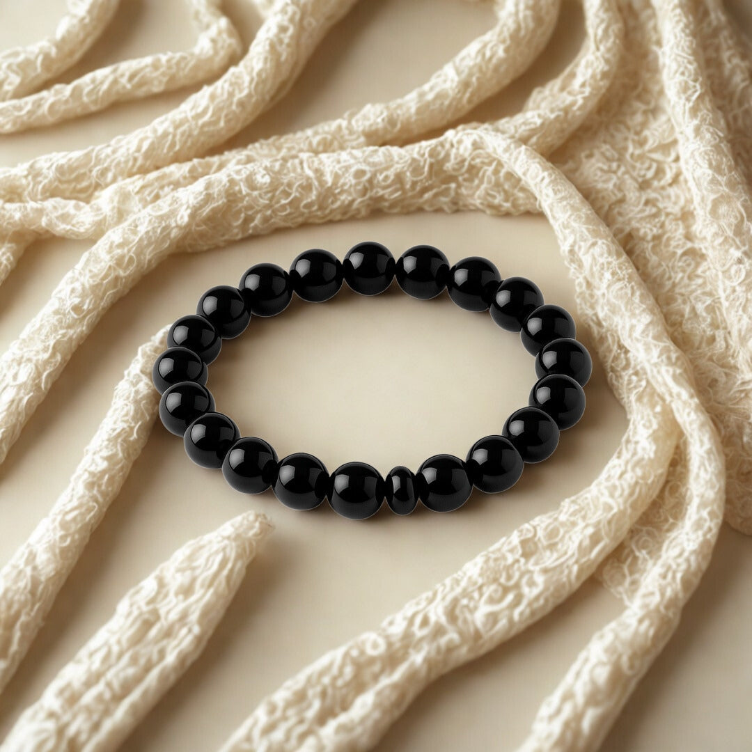 Black beaded bracelet on a textured beige surface