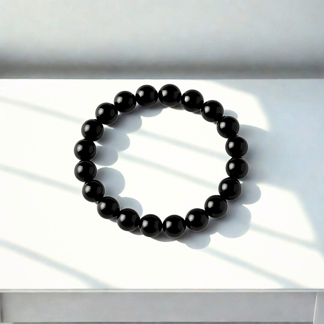 Black beaded bracelet on a white surface with soft shadows