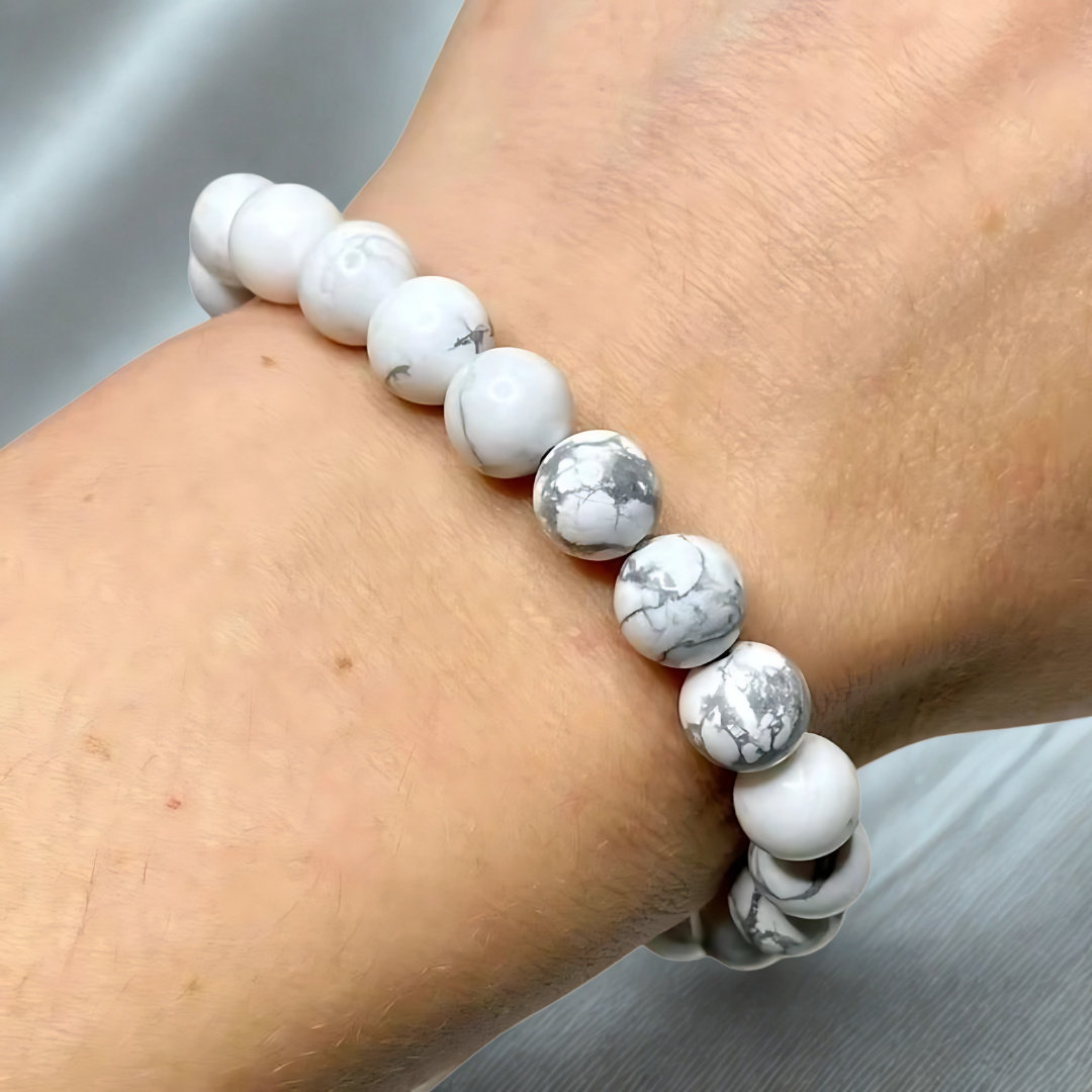 White and gray beaded bracelet on a wrist against a neutral background