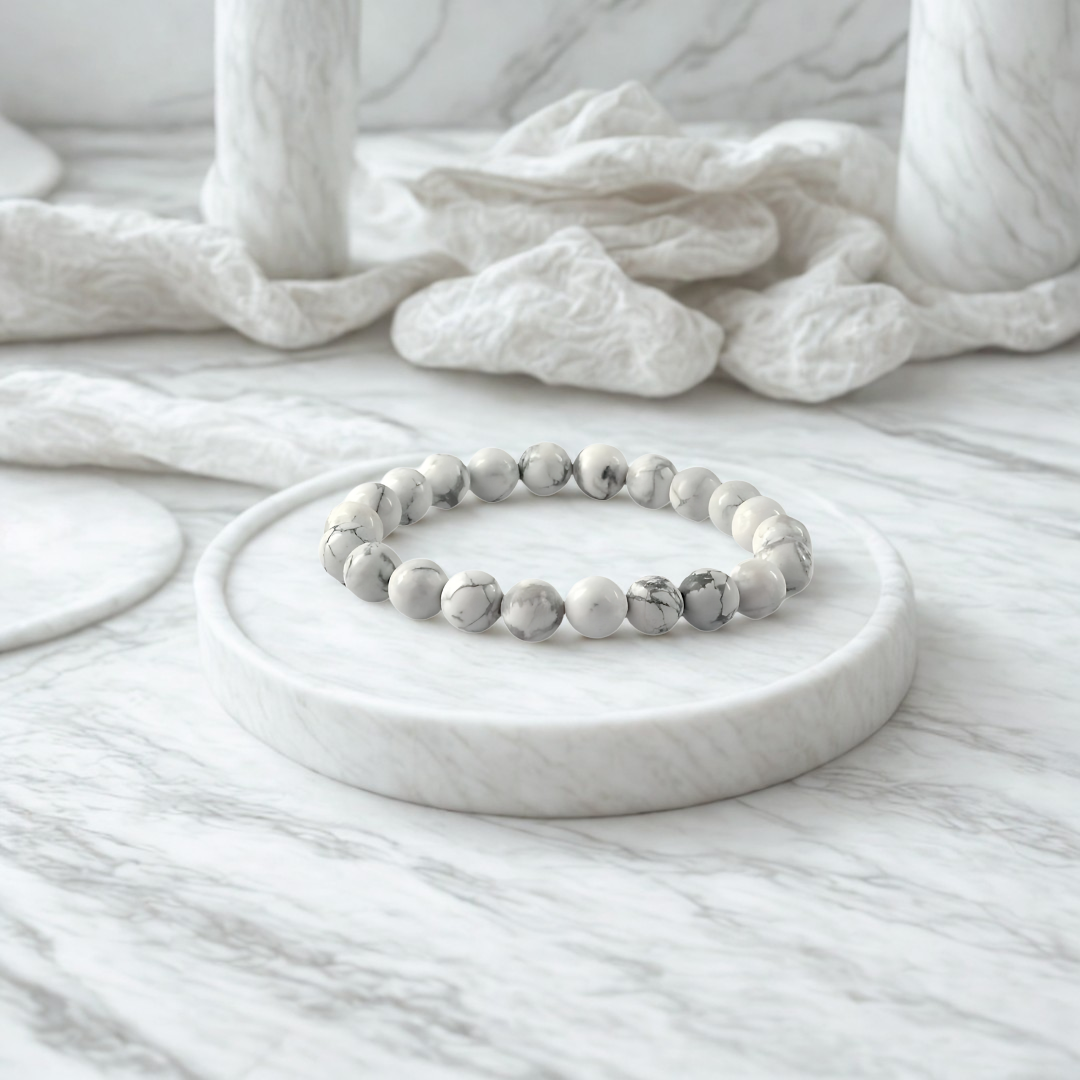 White beaded bracelet on a marble surface with a textured white fabric background