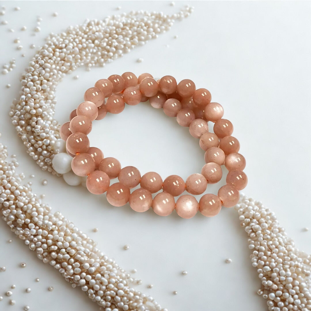 Pink beaded bracelet on a white background with scattered pearls