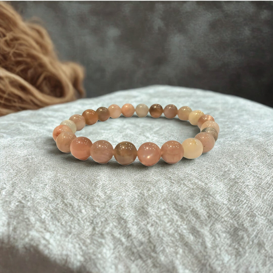 Beaded bracelet with peach-colored beads on a textured surface