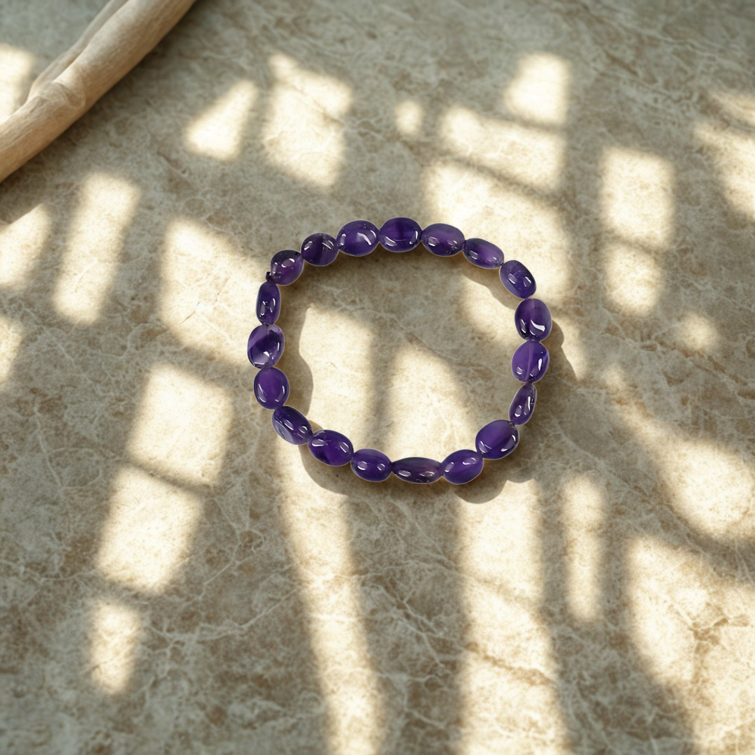 Purple beaded bracelet on a textured surface with shadows