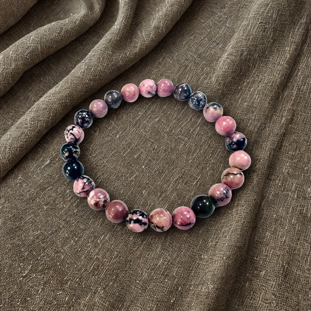Beaded bracelet with pink and black marbled beads on a brown fabric background
