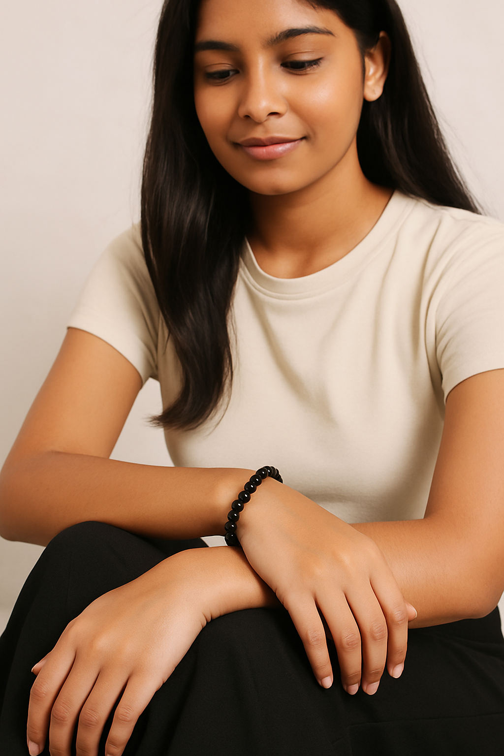 Woman wearing a beige t-shirt and black pants with a plain background
