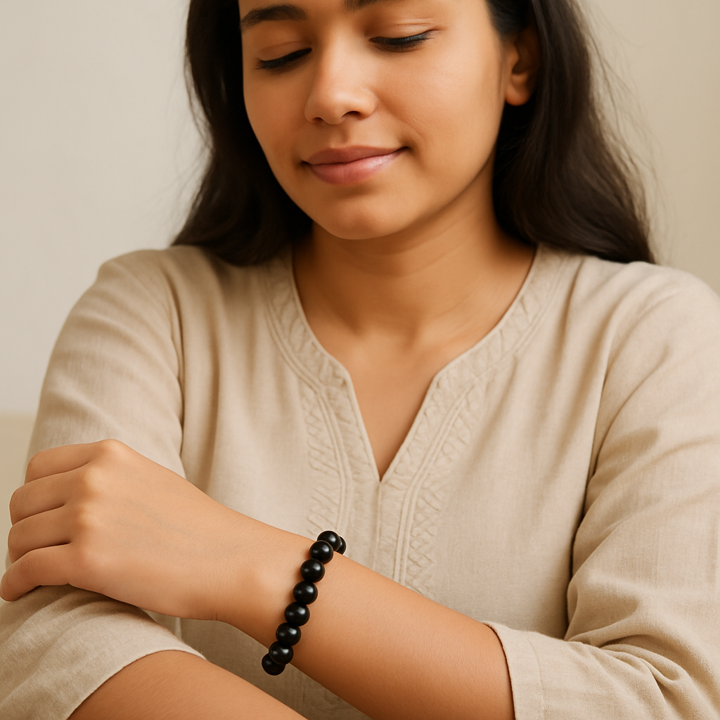 Woman wearing a black beaded bracelet on her wrist, sitting against a neutral background.