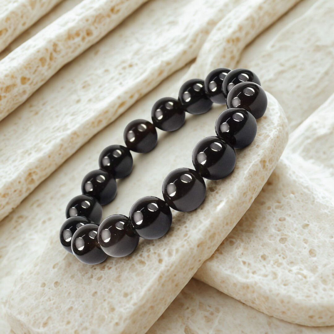 Black beaded bracelet on a textured beige surface