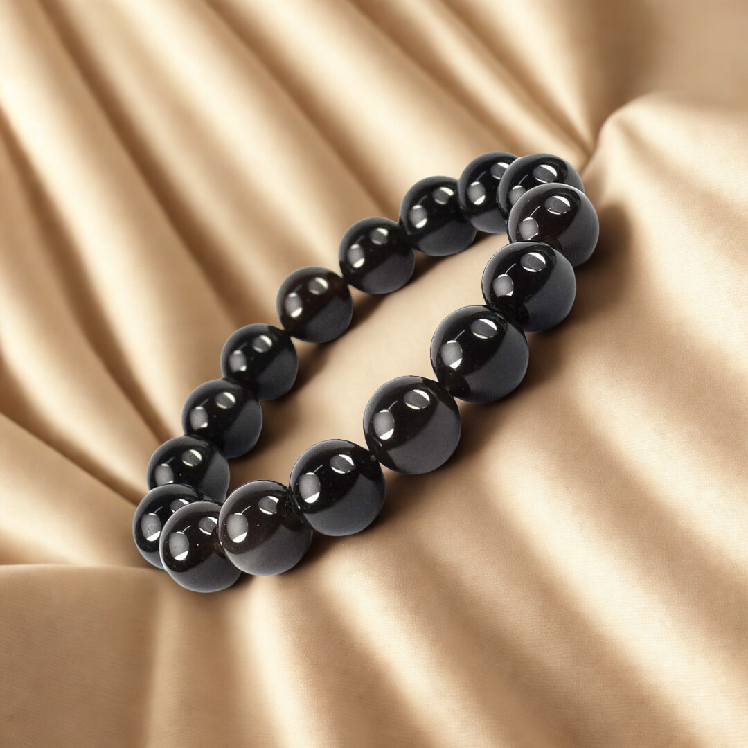 Black beaded bracelet on a beige fabric background
