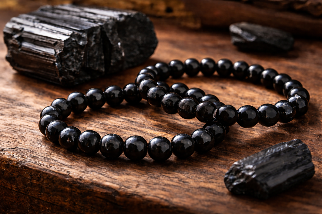 Black tourmaline gemstone bead bracelets with raw black tourmaline crystal on wooden surface, used for protection and energy cleansing