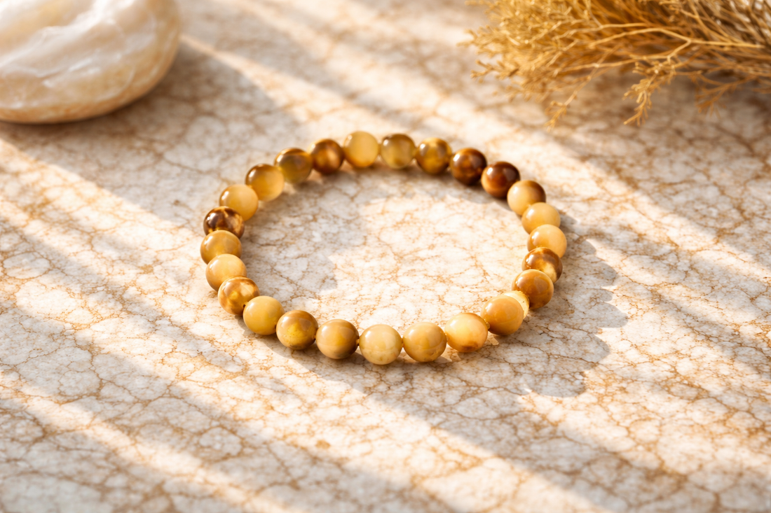 Natural yellow cat’s eye gemstone bracelet with polished beads placed on a marble surface in soft sunlight, highlighting its chatoyancy effect