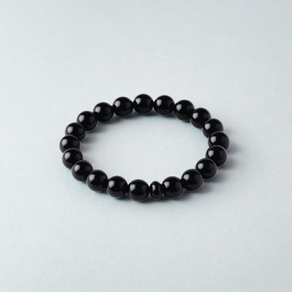 Black beaded bracelet on a light gray background