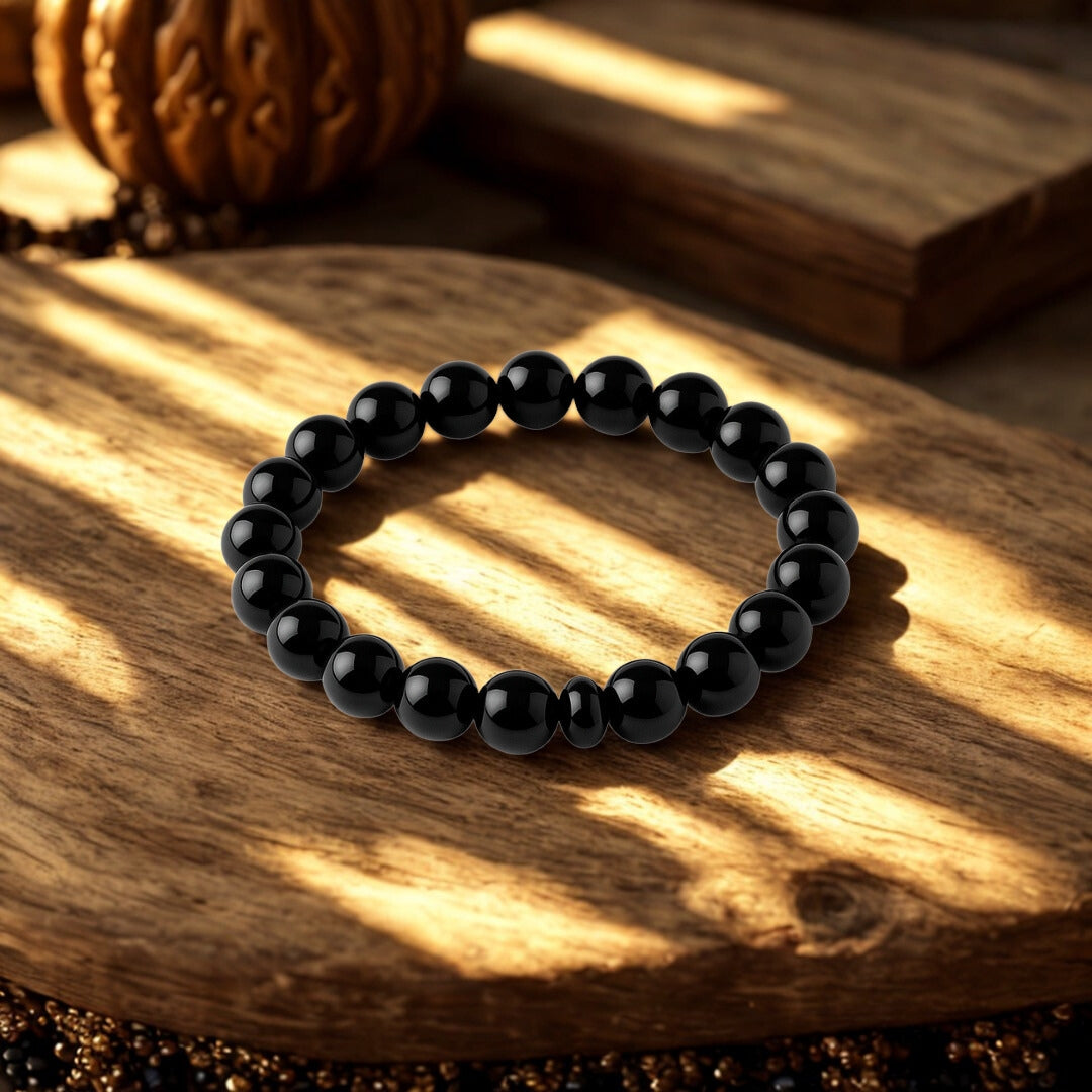 Black beaded bracelet on a wooden surface with warm lighting