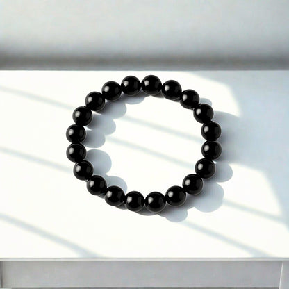 Black beaded bracelet on a white surface with soft shadows