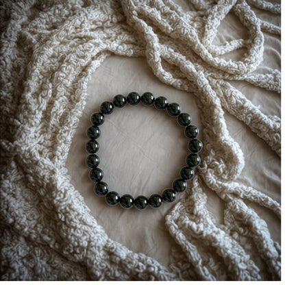 Black beaded bracelet on a textured beige fabric background