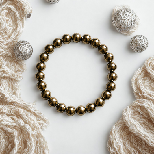 Golden Hematite Gemstone Bracelet  on a textured white surface with decorative silver beads.