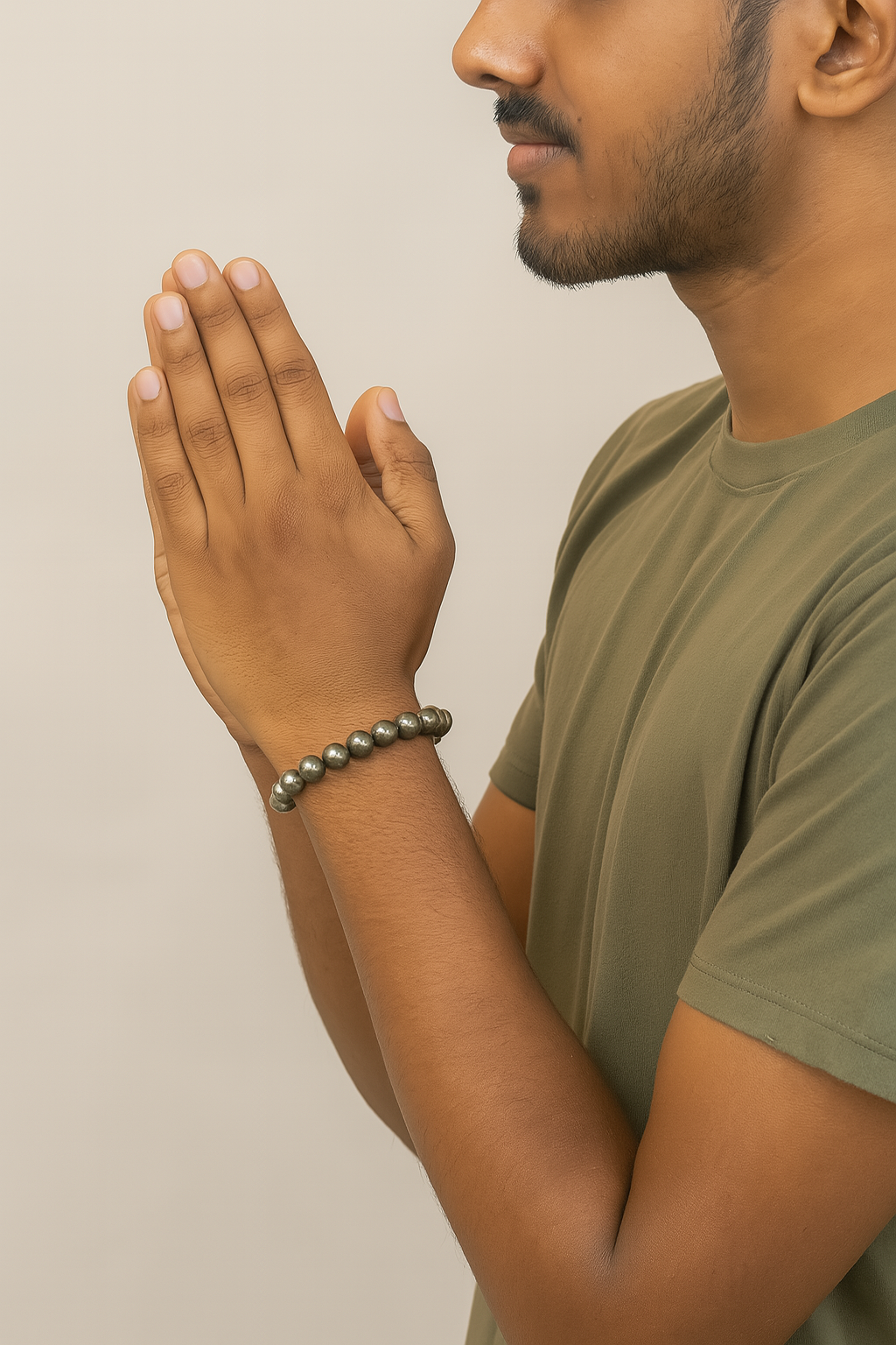 Man wearing a green shirt with his hands clasped together against a beige background