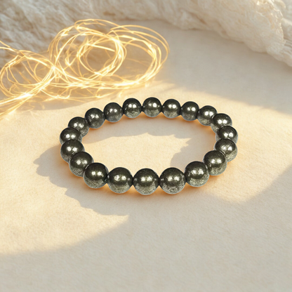 Black beaded bracelet on a light surface with string lights in the background