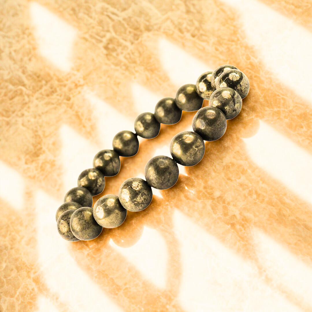 Brass beaded bracelet on a textured beige surface