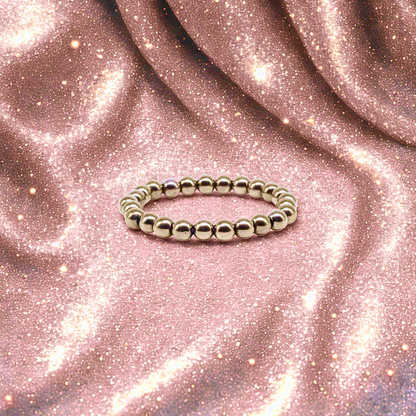 Silver beaded ring on a pink glittery fabric background