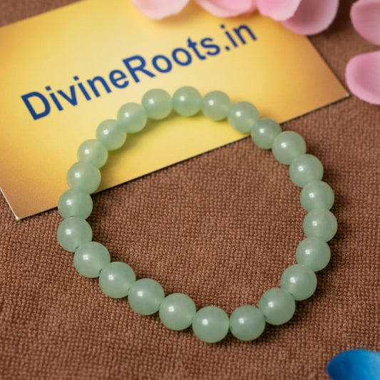 Natural Green Aventurine Bracelet  on a brown surface with 'DivineRoots.in' paper in the background