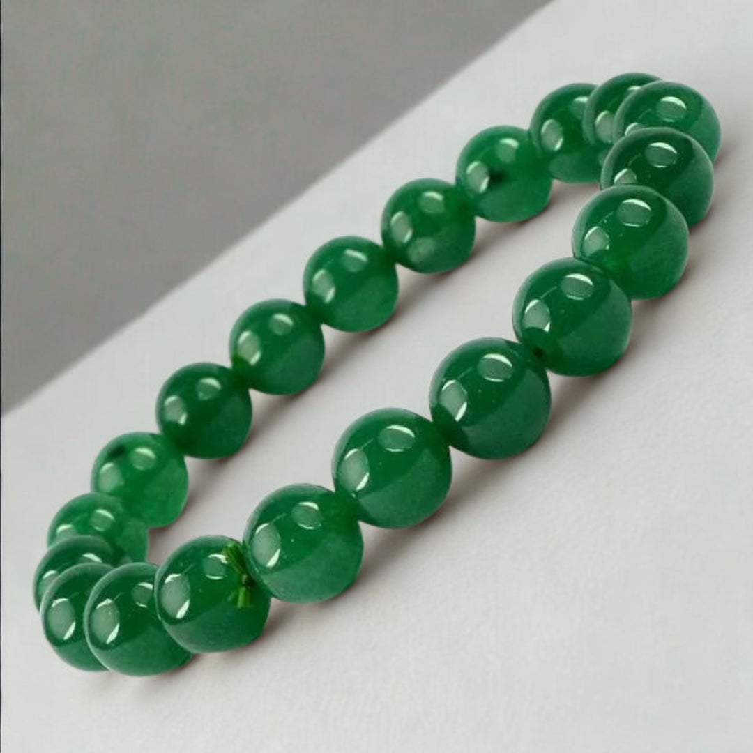 Green beaded bracelet on a white surface with a gray background