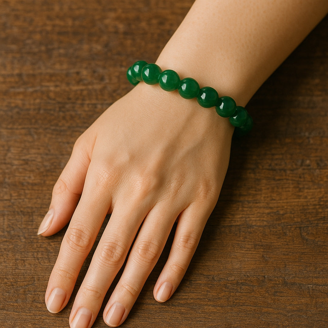 Hand wearing a green beaded bracelet on a wooden surface