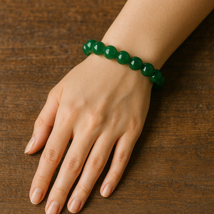 Hand wearing a green beaded bracelet on a wooden surface