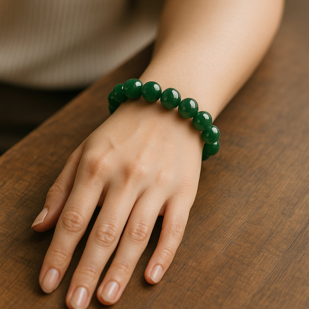 Hand wearing a green beaded bracelet on a wooden surface