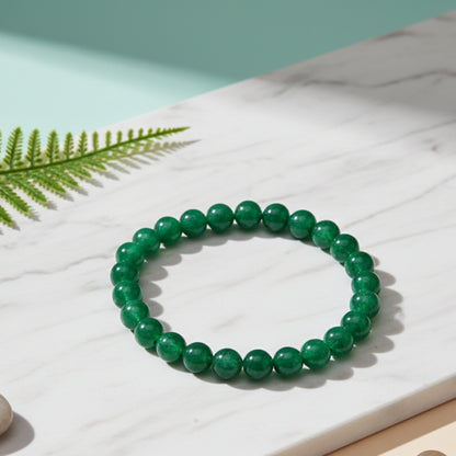 Green beaded bracelet on a light surface with a fern leaf
