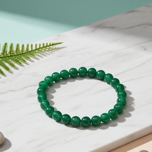 Green beaded bracelet on a light surface with a fern leaf