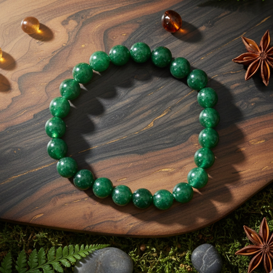 Green beaded bracelet on a wooden surface with star anise and stones.