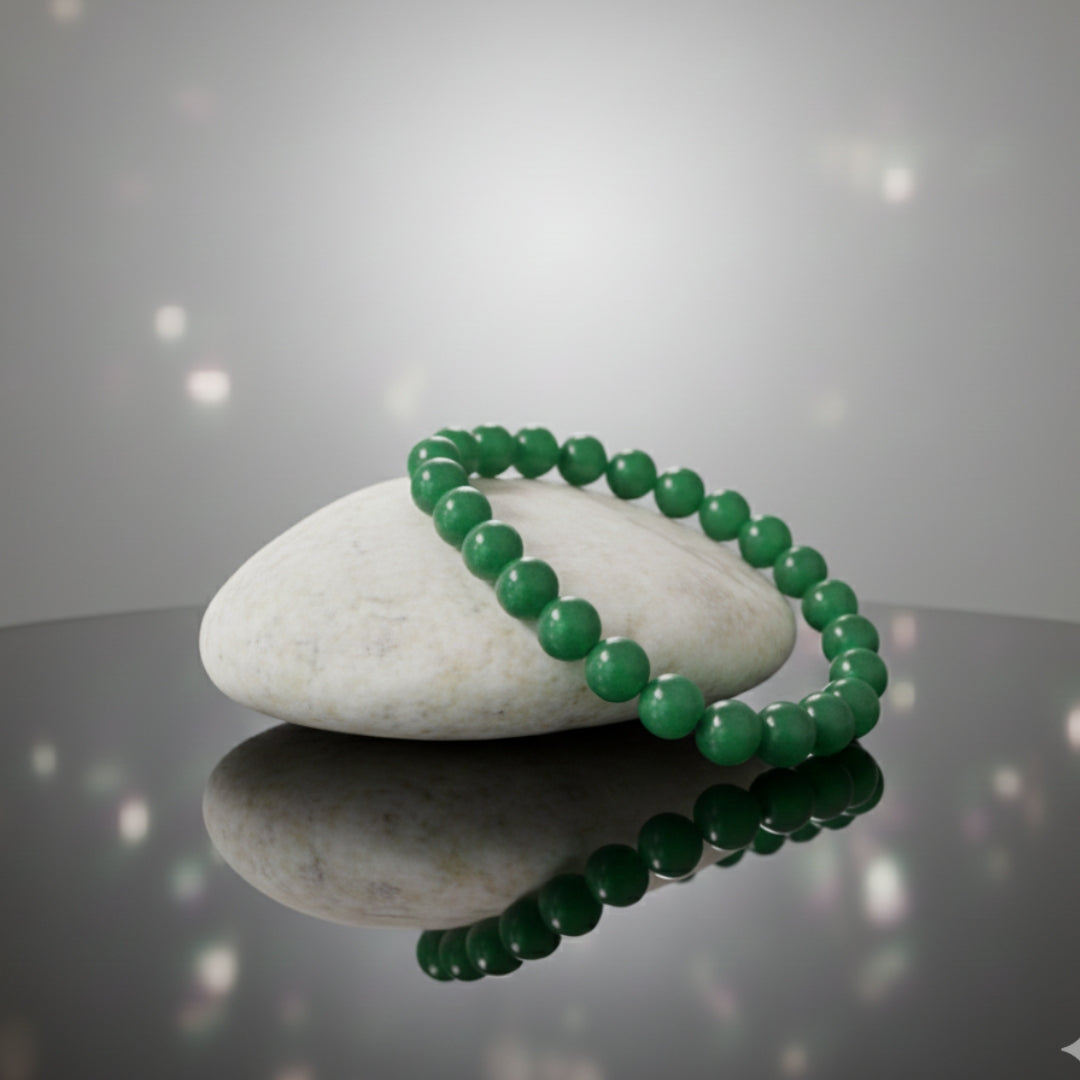 Green beaded bracelet on a white stone with a reflective surface and light gray background