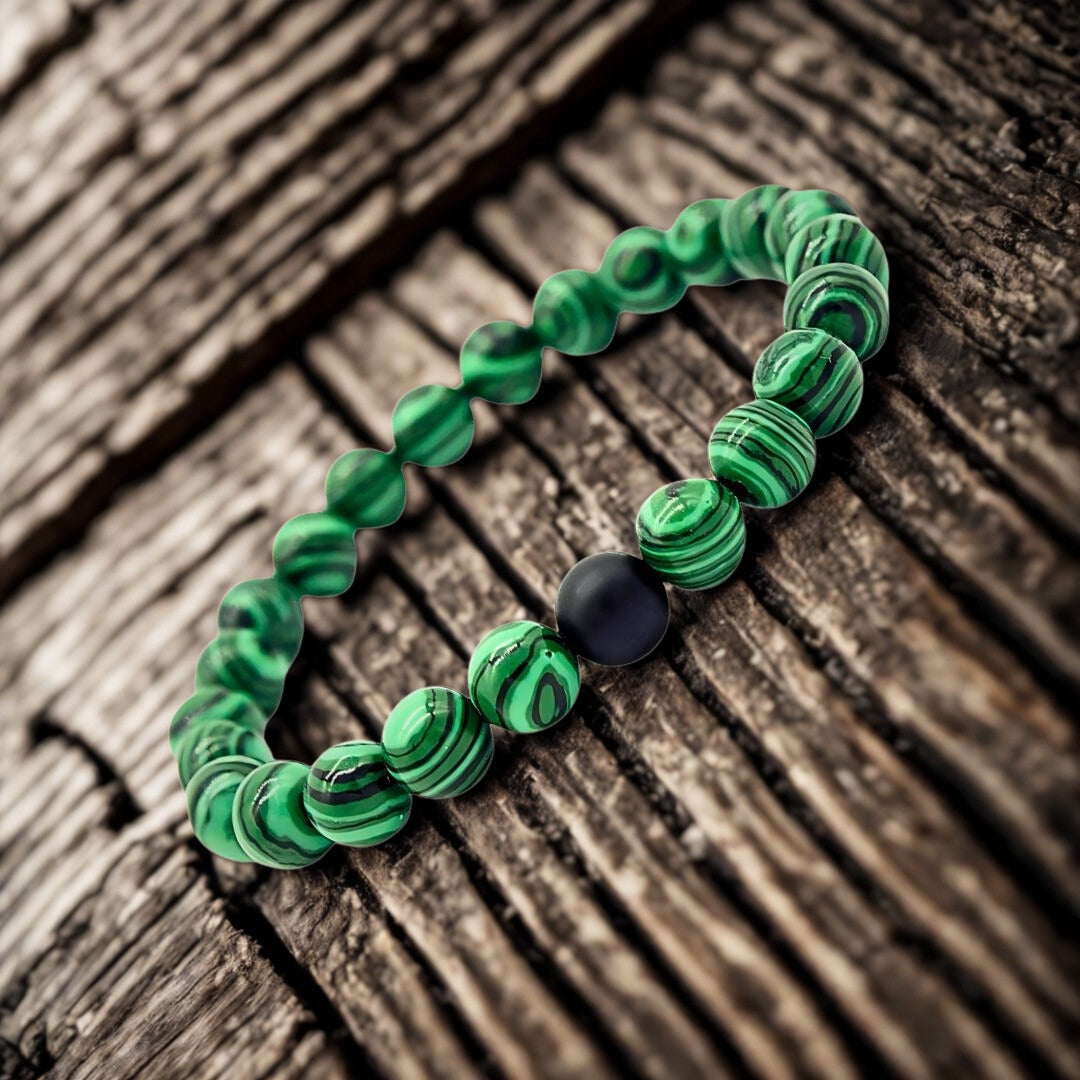 Green beaded bracelet with a black bead on a wooden surface