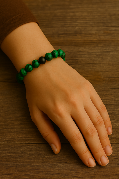 Hand wearing a green beaded bracelet on a wooden surface