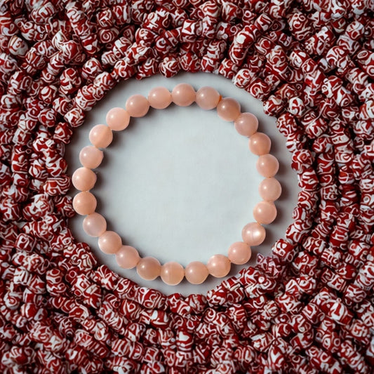 Natural Peach Moonstone Gemstone Bracelet on a white background with red patterned beads surrounding it