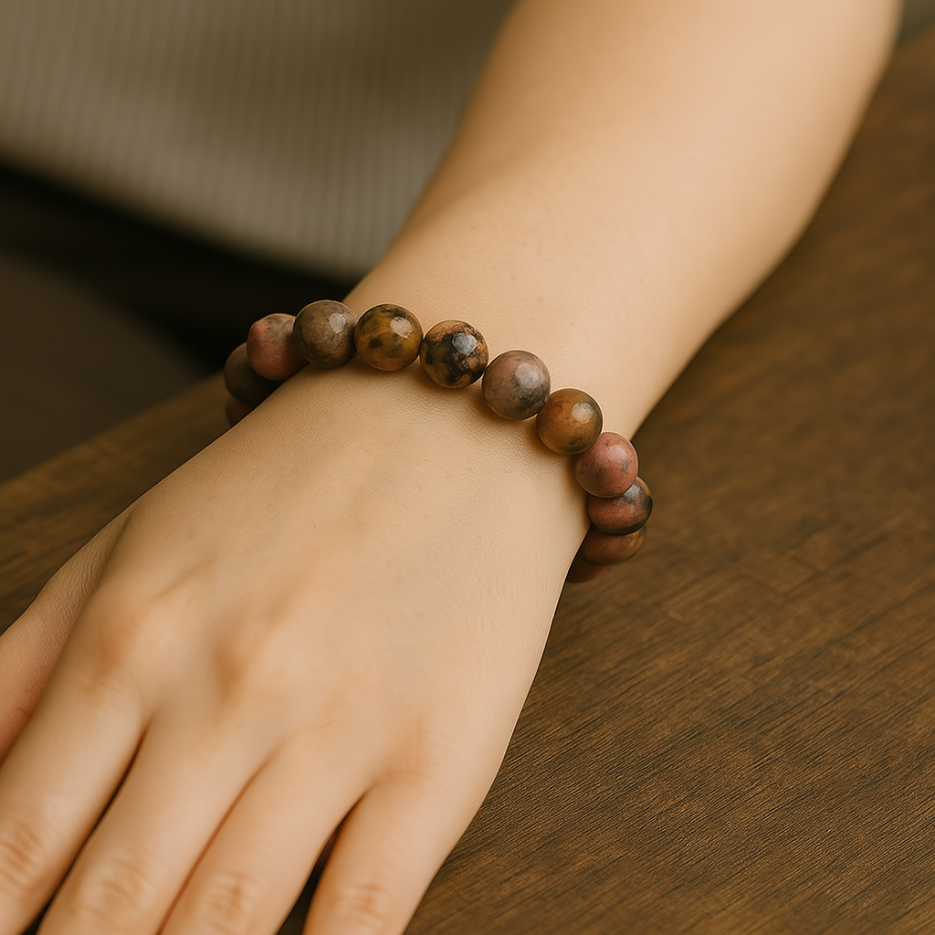 Hand wearing a beaded bracelet on a wooden surface