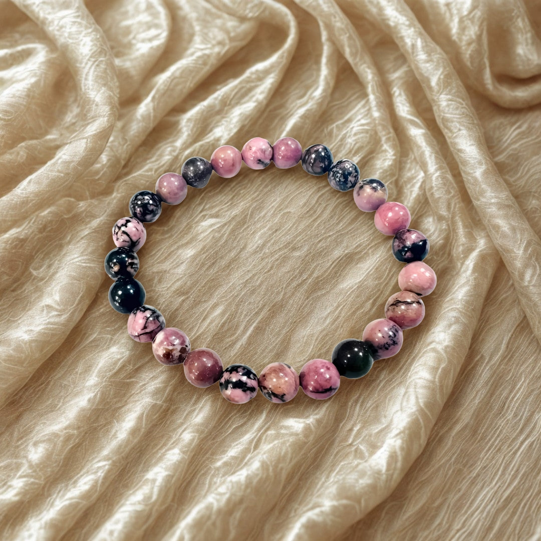 Bracelet with pink and black marbled beads on a beige fabric background