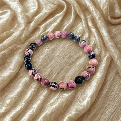 Bracelet with pink and black marbled beads on a beige fabric background