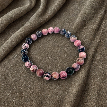 Beaded bracelet with pink and black marbled beads on a brown fabric background