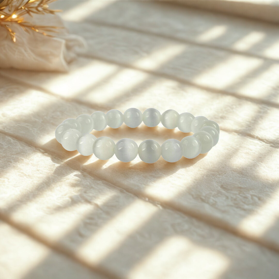 White beaded bracelet on a light wooden surface with natural light casting shadows.