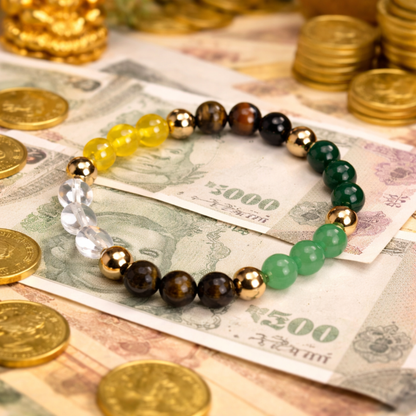 Dhan Yog bracelet with gold, brown, and green beads on a background of  notes and gold coins.