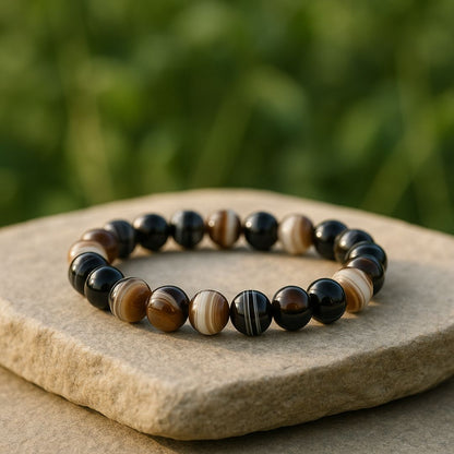 Black Sulemani Hakik bracelet on a stone surface with a blurred green background