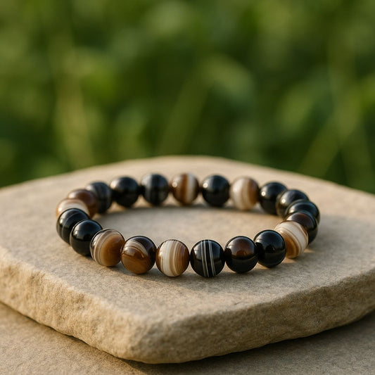 Black Sulemani Hakik bracelet on a stone surface with a blurred green background