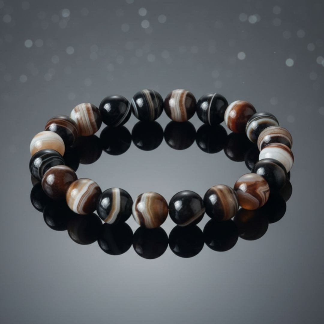 black sulemani hakik bracelet with black, brown, and white stones on a dark background