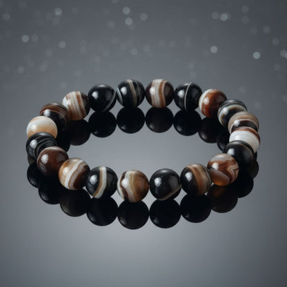 black sulemani hakik bracelet with black, brown, and white stones on a dark background
