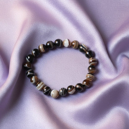 black sulemani hakik bracelet on a soft pink fabric background