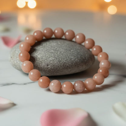 Muted peach Sunstone bracelet around a grey stone with warm background lights