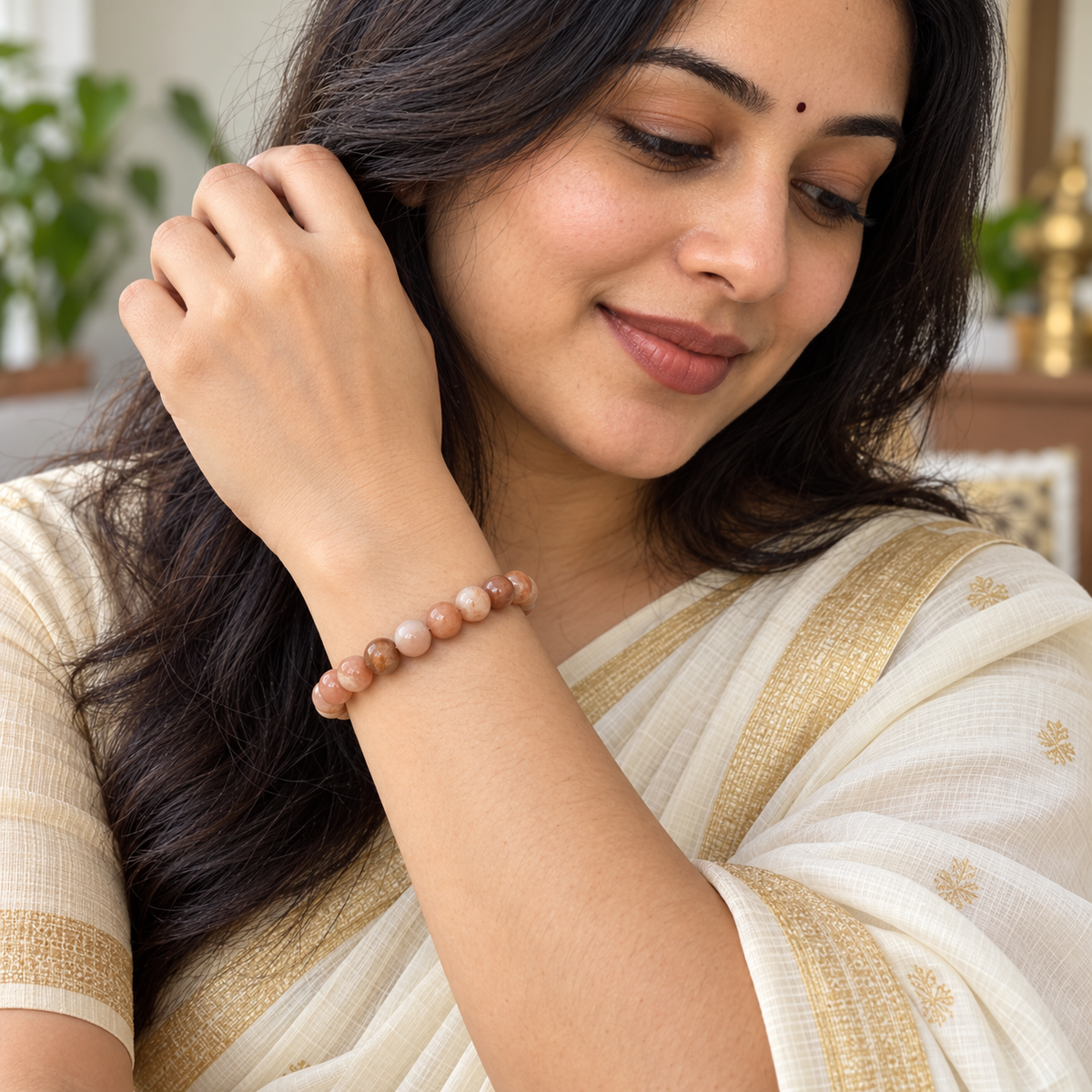 Close-up of a Sunstone bracelet worn with a traditional ivory saree
